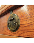 Close-up of brass ring pull handle on natural wood drawer with visible grain finish.
