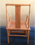 Natural wood chair with wide vertical backrest and armrests on a blue carpeted floor.