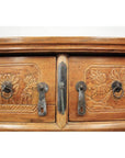 Close-up of natural elmwood cabinet doors with carved floral designs, metal handles, and keyholes.