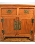 Natural wood small cabinet with two top drawers, two lower doors, and distinctive metal hardware, front view.