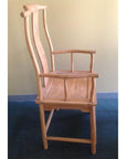 Natural wood yoke back chair with a tall, curved backrest against a pale yellow wall.