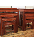 Brown wood nesting tables with carved geometric designs on a light-finished wooden floor.