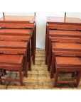 Reddish rosewood nesting tables, two sets placed side by side on a wooden floor.
