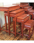 Wooden nesting tables with carved details, four sets arranged on a wooden floor, side-by-side display.