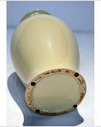 Off-white crackle porcelain vase with a cracked glaze and four black pads on the base, close-up view.