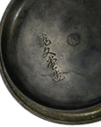 Close-up of dark metal Japanese teapot with engraved Asian characters, angled view.