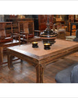 Black lacquer coffee table with two yellow cups and striped vase, surrounded by wooden chairs in a cozy room.