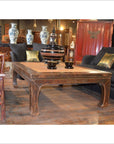 Black lacquer coffee table with elm horse hoof legs, styled in a living room with black couches and decorative vases.