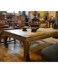 Black lacquer coffee table with bowls and vase, surrounded by sofas and wooden chairs in a vintage-style room.