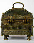 Brass Orissa miniature treasure box with intricate patterns, rounded lid, handle, and four short legs, close-up view.