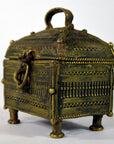 Brown metal Orissa miniature treasure box with decorative lid, intricate patterns, latch, and four short legs, close-up.