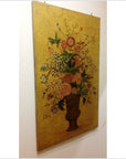 Colorful flower painting in an urn vase on a yellow background, displayed against a white wall.