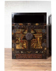 Black lacquered wooden Chinese display cabinets with hand painted chinoiserie motifs, set against a white brick wall.