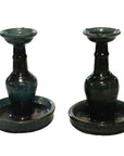 Close-up of antique Chinese Hunan candle holders with dark green glaze, wide bases, and rounded trays.