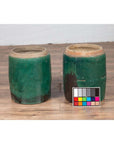Green glazed ceramic Chinese planters with brown patches on wooden floor beside a color chart, close-up.