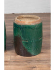 Green glazed ceramic Chinese planters with rustic finish on wooden floor against a white wall.