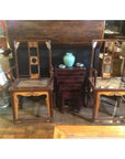 Pair of beige arm chairs with wood nesting tables, pale blue vase, and large decorative vase in living room setting.