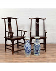 Brown wood Chinese Official's Hat Chairs from 1880s with carved splats, on wooden floor, white brick wall background.