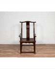 Pair of dark wood Chinese 1880s Official's Hat Chairs with carved splats on wooden floor against white brick wall.