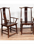 Pair of wood Chinese 1880s Official's Hat Chairs with carved splats on wooden floor by white brick wall.