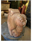 Brown wood Indian guardian lion carvings displayed among antiques in shop.