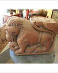 Brown wood Indian guardian lion carvings displayed indoors with other wooden sculptures and furniture in the background.