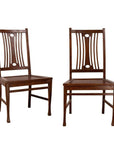 Brown wooden Indonesian side chairs with pierced splats, pair shown side by side on white background.