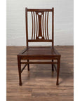 Brown wood Indonesian side chairs with pierced splats on a wooden floor against a white brick wall indoors.