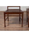 Brown wood Indonesian side chairs with pierced splats on wood floor, right chair partially cropped.