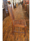 Teak armless chairs with high backrests on a polished floor in an antique furniture store.