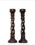Brown wooden vintage Indian candlesticks with spiral design and round bases on a white background, close-up view.
