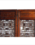 Brown wooden 2-panel screen with open fretwork design, used as room divider, indoor setting.