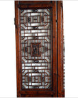 Brown wooden 2-panel screen with open fretwork design, used as a room divider, shown indoors.