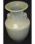 Light green porcelain vase with lion ring handle and wide mouth, close-up against a black background.
