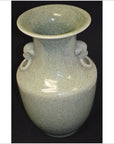 Light green porcelain vase with lion ring handle and wide mouth, close-up against a black background.