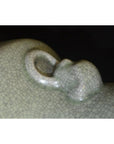Close-up of pale green porcelain vase with crackle celadon surface and lion ring handle.