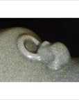 Close-up of pale green porcelain vase with crackle celadon surface and lion ring handle.