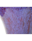 Close-up of purple, blue, and red glazed ceramic vase with textured surface on white background.