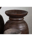 Close-up of brown wooden ghee pots with carved horizontal lines, rustic style, grouped together on a flat surface.