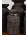 Brown wooden ghee pots in groups of three, five, or seven displayed with clay pots on a wooden surface.