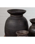 Brown wooden ghee pots in a rustic style, grouped together against a light brick wall.
