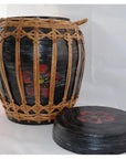 Black rattan and bamboo round lidded basket with woven wicker pattern, red flower designs on lid and sides, close-up.