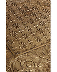 Close-up of silver hammered metal tiles with floral and geometric patterns overlapping on a small rectangular table.