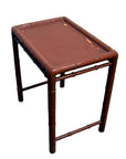 Red bamboo side table with small rectangular top and bamboo-style legs, close-up view.