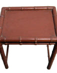 Close-up of a small, square red bamboo side table with bamboo-inspired legs and edges.