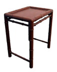 Red wooden bamboo-style side table with rectangular top and bamboo-inspired legs and edges, close-up view.