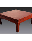 Red lacquer wood low chow leg table with curved legs set against a dark plain background.