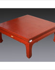 Red lacquer wood low chow leg table against a gradient gray background.