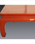 Close-up of red lacquer wood Low Chow Leg Table with square legs and distressed finish, set against grey background.