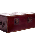 Close-up of red lacquer trunk with metal studs and dark reddish-brown handles, used as a coffee table.